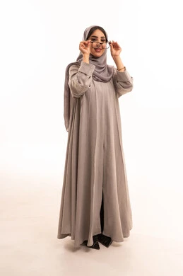 مفهوم ضعف النظر، اقتناء نظارات طبية جديدة، متعة التسوق في السعودية، تصحيح وتحسين الرؤية، بورتريه لامرأة عربية خليجية سعودية ترتدي الحجاب و العباءة تقوم باختيار نظارة ملائمة لملامح الوجه، الجسم بالطول الكامل، خلفية بيضاء