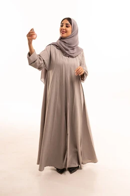 The use of natural essential oils, the concept of elegance and concern for appearance, a portrait of a Saudi Gulf Arab woman wearing a hijab and abaya spraying perfume, marketing for perfume and women's products, full-body, white background.