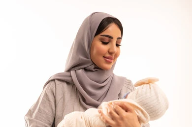 Spending beautiful moments with children, gestures of love and affection towards the little ones, the tenderness of mothers and the responsibility and care for children, a close-up portrait of an Arab Gulf Saudi woman wearing an abaya and hijab holding her daughter with love and tenderness, white background.