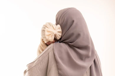 مساعدة الأطفال على الشعور بالراحة والسكينة، الشعور بالأمان في حضن الامهات, بورتريه مقرب من الخلف لإمرأة عربيه خليجيه سعوديه ترتدي العباءة و الحجاب تحمل طفلتها بحب وحنان، خلفية بيضاء