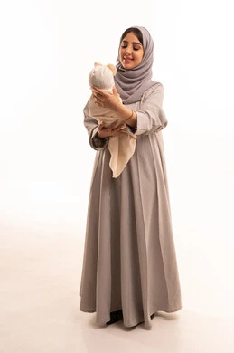 اهتمام الأمهات بأبنائهم, شعور الطفلة بالراحه والهدوء برفقه والدتها, بورترية لامراه عربيه خليجيه سعودية ترتدي العباءة و الحجاب تحمل ابنتها بلطف، دور الأم في تربيه وتنشأه الأولاد, مفهوم الأمومه والطفولة, الجسم بالطول الكامل، خلفيه بيضاء