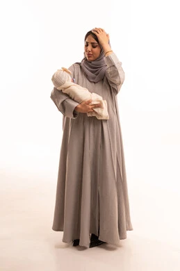 التذكر المفاجئ لشيء هام، الاهتمام والرعاية بالأبناء، مشاعر العطف والحنان، تقوية رابطة الأمومة ، بورترية لامراه عربيه خليجيه سعودية ترتدي العباءة و الحجاب تحمل طفلتها وتضع يدها على رأسها بايماءات تدل على النسيان , الجسم بالطول الكامل، خلفية بيضاء