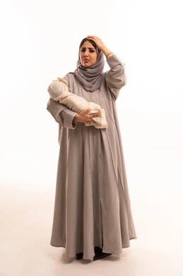 استحضار مفاجئ لشيء مهم، الاهتمام والرعاية بالأبناء، مشاعر العطف والحنان، تقوية رابطة الأمومة ، بورترية لامراه عربيه خليجيه سعودية ترتدي العباءة و الحجاب تحمل طفلتها وتضع يدها على رأسها بايماءات تدل على النسيان , الجسم بالطول الكامل، خلفية بيضاء