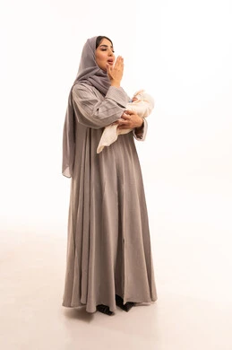 Caring for and nurturing children, the need for sleep and rest, feelings of affection and tenderness, strengthening the bond of motherhood, a portrait of an Arab Gulf Saudi woman wearing an abaya and hijab holding her daughter and yawning, full-body, white background. Caring for and nurturing children, the need for sleep and rest, feelings of affection and tenderness, strengthening the bond of motherhood, a portrait of an Arab Gulf Saudi woman wearing an abaya and hijab holding her daughter and yawning, full-body, white background.