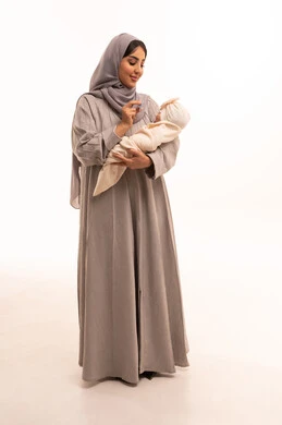 مشاعر العطف والحنان، تقوية رابطة الأمومة , الاهتمام والرعاية بالأبناء، بورترية لامراه عربيه خليجيه سعودية ترتدي العباءة و الحجاب تقوم بإعطاء طفلها اللهاية , الجسم بالطول الكامل، خلفية بيضاء