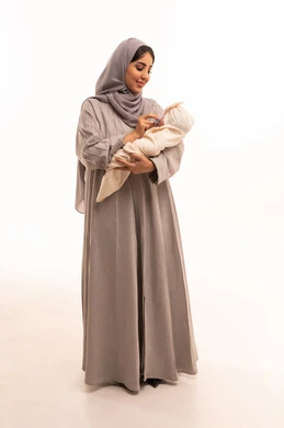 الاهتمام والرعاية بالأبناء، تقوية رابطة الأمومة ، بورترية لامراه عربيه خليجيه سعودية ترتدي العباءة و الحجاب تقوم بإعطاء طفلها اللهاية ،مشاعر العطف والحنان , الجسم بالطول الكامل، خلفية بيضاء