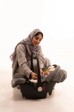 Helping sons and daughters to relax and calm down, mothers' care and attention to children, feelings of compassion and tenderness, a portrait of an Arab Gulf Saudi woman wearing an abaya and hijab looking at her infant daughter with gestures of happiness and love, full-body, white background.