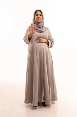 الشعور بالإنزعاج والغضب، تعابير الرفض والإمتناع، الأمر بالتوقف عن فعل شيء ما،بورترية لامراه عربيه خليجيه سعودية حامل ترتدي العباءة و الحجاب ترفع يدها بإيماءات تدل على النهي، صورة الجسم بالطول الكامل، خلفية بيضاء