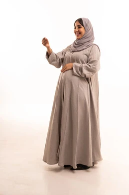 الهدوء وطلب التوقف،  بورترية من الجانب لامراه عربيه خليجيه سعودية حامل ترتدي العباءة و الحجاب تنظر الى الكاميرا بسرور وسعادة، الاشارة بإيماءات الصبر والتأن والتريث، إمهال الوقت والإنتظار للقيام بشيء ما، الجسم بالطول الكامل، خلفية بيضاء