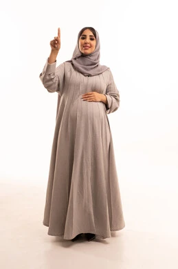 تحديد موقع معين، إشارات وحركات يدين تدل على هذا المكان (هنا)، بورترية لامراه عربيه خليجيه سعودية حامل تنظر إلى الكاميرا ترفع أصابعها السبابة تشير إلى الاعلى، الجسم بالطول الكامل، خلفية بيضاء