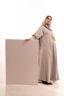 العروض والإعلانات التسويقية, بورترية لامراه عربيه خليجيه سعودية حامل ترتدي العباءة و الحجاب تمسك بيديها لوحة بيضاء مستطيلة فارغة، لوحات توضيحية ووسائل تعليمية, موك اب مستطيل أبيض, الجسم بالطول الكامل، خلفية بيضاء