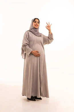 Quality and excellence mark, the concept of acceptance and approval, a portrait of a pregnant Saudi Gulf Arab woman wearing an abaya and hijab, raising her hand with gestures indicating admiration and satisfaction, looking at the camera with expressions of joy and happiness, full-body image, white background.