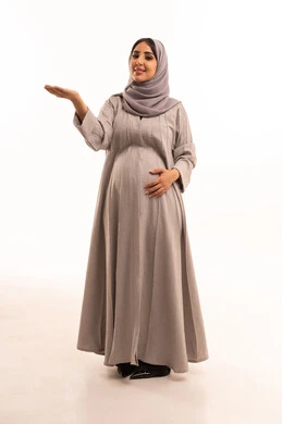 الإشارة إلى عنصر ما, التوضيح والدلالة لمكان محدد, بورتريه لامرأة عربية خليجية سعودية حامل ترتدي العباءة و الحجاب تشير بيديها على الجانب، تحديد موقع شيء معين, صورة الجسم بالطول الكامل، خلفية بيضاء