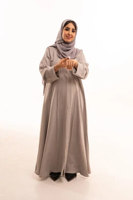 مفهوم الاهتمام بالجسد، استخدام كريم ومكون تجميلي، النظر بإيماءات السرور، العناية بنضارة وتحسين البشرة، بورتريه لامرأة عربية خليجية سعودية حامل ترتدي العباءة و الحجاب تقوم بوضع كريم على يديها، صورة الجسم بالطول الكامل، خلفية بيضاء