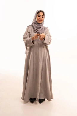 Using cream and cosmetic ingredients, looking with gestures of joy, the concept of caring for the freshness and improvement of the skin, a portrait of a pregnant Saudi Gulf Arab woman wearing an abaya and hijab applying cream to her hands, full-body image, white background.