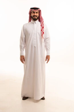 النظر الى الكاميرا بتعابير السرور، مفهوم الرجولة والثقة بالنفس، الأناقة والاهتمام بالمظهر الخارجي،، بورتريه من الجانب لرجل عربي خليجي سعودي يرتدي الشماغ والزي التقليدي يقف باستقامه و اعتدال ، الجسم بالطول الكامل، خلفية بيضاء