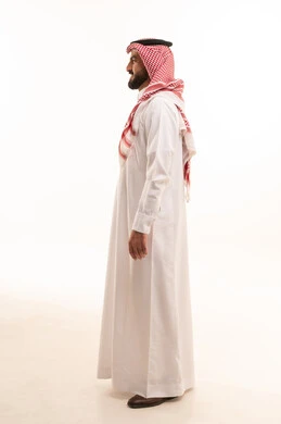 مفهوم الرجولة والثقة بالنفس، الأناقة والاهتمام بالمظهر الخارجي،، بورتريه من الجانب لرجل عربي خليجي سعودي يرتدي الشماغ والزي التقليدي يقف باستقامه و اعتدال ، الجسم بالطول الكامل، خلفية بيضاء
