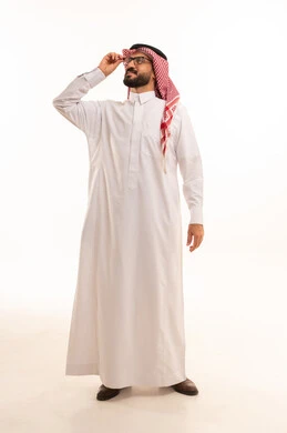 مفهوم تحسين الرؤية ومحاولة تعديل البصر، الاهتمام بالمظهر الخارجي، ارتداء النظارات الخاصة بضعف النظر، بورتريه لرجل عربي خليجي سعودي يرتدي الثوب الابيض و الشماغ يضع على وجهه نظارة طبية و ينظر الى شيء ما, الجسم بالطول الكامل، خلفية بيضاء