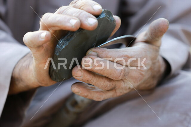 مزارع عربي خليجي يقوم بسن المنجل الزراعي ، اداة الحصاد ،ادوات قديمة تستخدم في الزراعة ، الزراعة في المملكة العربية السعودية