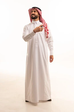 التسويق لمنتجات العطور, مفهوم التعطر والتطيب، عطورات خليجية سعودية, الاهتمام بالمظهر الخارجي, استخدام الزيوت العطرية الطبيعية, بورتريه لرجل عربي خليجي سعودي يرتدي الثوب الابيض و الشماغ يقوم برش العطر, صورة الجسم بالطول الكامل, خلفية بيضاء