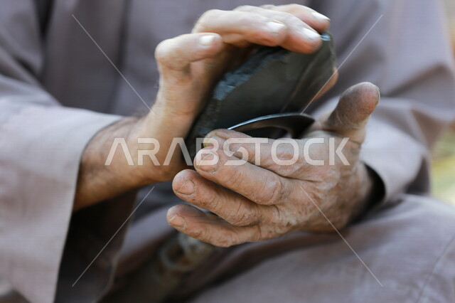 An Arab Gulf farmer sharpening the agricultural sickle, harvesting tool, old tools used in agriculture, agriculture in the Kingdom of Saudi Arabia