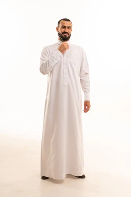 الاهتمام بالمظهر الخارجي والأناقة الشخصية، بورتريه لرجل عربي خليجي سعودي يرتدي الثوب الابيض يقوم بتمشيط ذقنه باستخدام ( المشط )، تعابير وإيماءات تدل على السعادة والسرور، الجسم بالطول الكامل، خلفية بيضاء