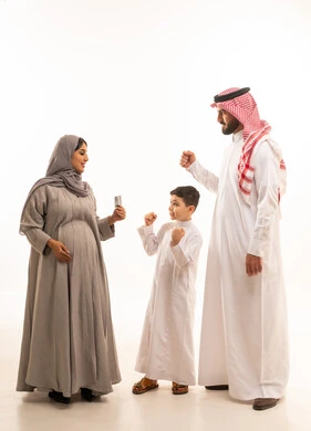 تعابير الانجاز و تحقيق النجاح، متابعة مراحل الحمل والجنين من خلال جهاز السونار، مفهوم الحمل و الانجاب، بورترية من الجانب لامراة حامل عربيه خليجيه سعودية ترتدي العباءة و الحجاب تحمل بيديها اشعه الفوق صوتية برفقة ابنها و زوجها، الجسم بالطول الكامل، خلفية بيضاء