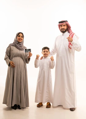 Conducting a regular ultrasound examination for the fetus, expressions of victory and achieving success, the concept of pregnancy and childbirth, a portrait of a pregnant Arab Gulf Saudi woman wearing an abaya and hijab holding a sonogram in her hands accompanied by her son and husband, full-body, white background.