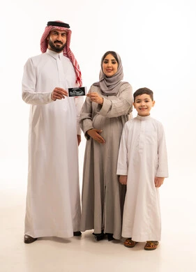 استخدام تقنية السونار لفحص الجنين داخل الرحم، بورترية لرجل عربي خليجي سعودي يرتدي الثوب الابيض و الشماغ يمسك بيديه اشعه السونار برفقة زوجته و ابنه، مفهوم الحمل و الانجاب، ايماءات السعادة و السرور، الجسم بالطول الكامل، خلفية بيضاء