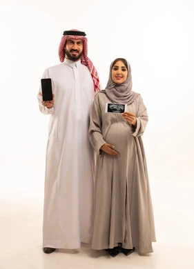 Using ultrasound to reassure about the baby, a portrait of a Saudi Arabian Gulf man wearing a white thobe and a ghutrah displaying a black screen on a mobile phone, a pregnant Saudi Gulf woman wearing an abaya and hijab holding the ultrasound images in her hands, the concept of pregnancy and childbirth, full-body, white background.
