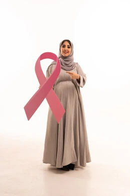 رمز الحملة العالمية، الحملة التوعيه بالامراض الخبيثة, مفهوم الحمل و الانجاب، بورتريه لامراة عربية خليجية سعودية محجبة مبتسمة ترتدي العباءة تشير بيدها الى شعار التوعيه للكشف المبكر لسرطان الثدي، الجسم بالطول الكامل، خلفية بيضاء