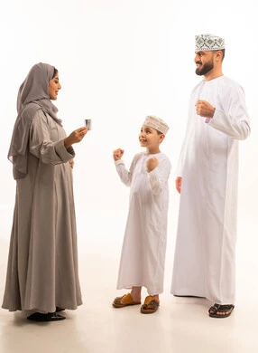 متابعة مراحل الحمل والجنين من خلال جهاز السونار، تعابير الانجاز و تحقيق النجاح، مفهوم الحمل و الانجاب، بورترية من الجانب لامراة حامل عربيه خليجيه عمانية ترتدي العباءة و الحجاب تحمل بيديها اشعه الفوق صوتية برفقة ابنها و زوجها، الجسم بالطول الكامل، خلفية بيضاء