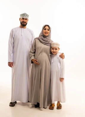 المشاعر العائلية الدافئة والترابط الأسري، مفهوم الحمل و الانجاب، بورترية لعائلة عربيه خليجيه عمانية ترتدي الزي التقليدي تنظر الى الكاميرا بتعابير السعادة و السرور ، الجسم بالطول الكامل، خلفية بيضاء
