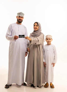 استخدام تقنية السونار لفحص الجنين داخل الرحم، بورترية لرجل عربي خليجي عماني يرتدي الدشداشة و الكمة يمسك بيديه اشعه السونار برفقة زوجته و ابنه، مفهوم الحمل و الانجاب، ايماءات السعادة و السرور، الجسم بالطول الكامل، خلفية بيضاء