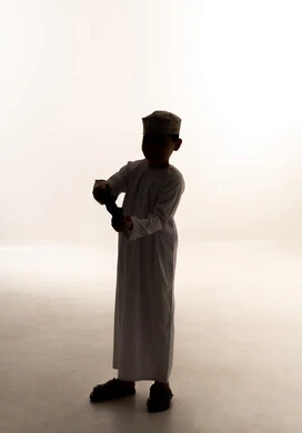 اجهزة وتقنيات الكترونية حديثة ترفيهيه, قضاء وقت ممتع ومسلي، التفاعل والاندماج مع ألعاب الفيديو والبلايستيشن،, صورة ظلية لولد ربي خليجي عماني يرتدي الدشداشة و الكمة يحمل بيده عصا التحكم، الجسم بالطول الكامل، خلفية بيضاء، سولوليت