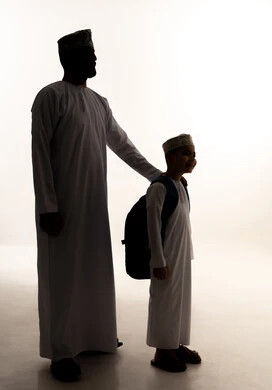 Preparing for the start of a new school year, caring for and nurturing children, the back-to-school season in Oman, the feeling of safety and love with parents, a side silhouette of an Omani Gulf Arab boy wearing a dishdasha and kumma carrying a backpack alongside his father, full body, white background, silhouette. Preparing for the start of a new school year, caring for and nurturing children, the back-to-school season in Oman, the feeling of safety and love with parents, a side silhouette of an Omani Gulf Arab boy wearing a dishdasha and kumma carrying a backpack alongside his father, full body, white background, silhouette.