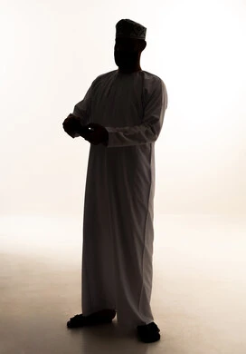 Modern electronic entertainment devices and technologies, spending enjoyable and entertaining time, interacting and engaging with video games and PlayStation, a silhouette of an Arab Gulf Omani man wearing a dishdasha and kumma holding a game controller in his hands, full-body, white background, silhouette.