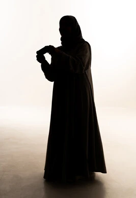 Modern electronic entertainment devices and technologies, spending enjoyable and entertaining time, interacting and engaging with video games and PlayStation, a silhouette of an Arab Gulf Saudi woman wearing an abaya and hijab holding a game controller in her hands, full-body, white background, silhouette.