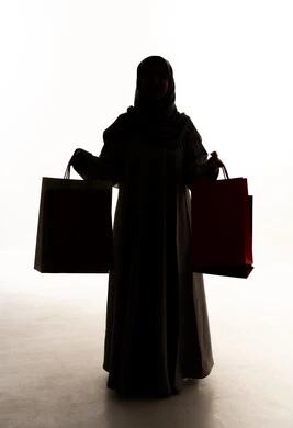 الأثر الإيجابي للتسوق على السيدات، الاستفادة من العروض الموسمية والتخفيضات، التبضع والتسوق من الماركات العالميه، صورة ظلية لامراه عربيه خليجيه سعودية ترتدي العباءة و الحجاب تحمل بيدها أكياس التسوق ، الجسم بالطول الكامل، خلفية بيضاء