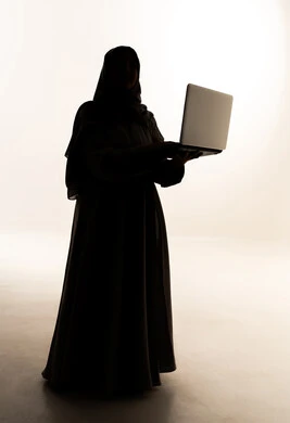Managing and organizing business affairs, browsing the internet and using modern technological devices, a silhouette of an Arab Gulf Saudi woman wearing an abaya and hijab working on a laptop, working to achieve goals and strategies, completing tasks remotely, full body background, white background, silhouette.