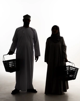 Buying necessary supplies and essentials, enjoying shopping in malls and commercial centers, taking advantage of offers and discounts, a silhouette of an Arab couple from the Gulf, Omani, wearing traditional attire carrying a shopping basket, buying products from the supermarket, full-body, white background, silhouette.