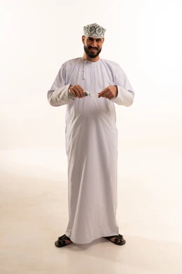 الحفاظ على الأسنان وتنظيفها بشكل مستمر، استخدام الفرشاة والمعجون، مفهوم العادات الصحية, ابتسامة ناصعة البياض, روتين نظافة الفم اليومية، تجنب التسوس وأمراض اللثة, بورتريه لرجل عربي عماني خليجي يرتدي الدشداشة و الكمة يقوم بغسل اسنانه، الجسم بالطول الكامل، خلفية بيضاء