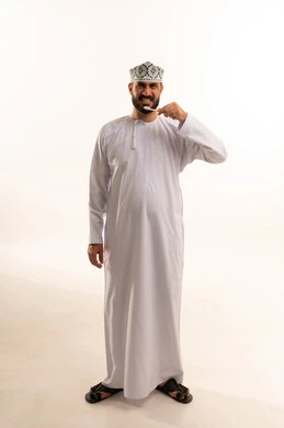 الحفاظ على الأسنان وتنظيفها بشكل مستمر, مفهوم العادات الصحية, ابتسامة ناصعة البياض, روتين نظافة الفم اليومية، تجنب التسوس وأمراض اللثة, بورتريه لرجل عربي عماني خليجي يرتدي الدشداشة و الكمة يقوم بغسل اسنانه باستخدام الفرشاة ، الجسم بالطول الكامل، خلفية بيضاء