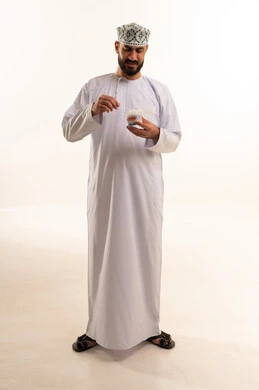 العناية والاهتمام بصحة الأذن، استخدام أعواد ونكاشات القطن، روتين نظافة الأذنين اليومية، بورتريه لرجل عربي عماني خليجي يرتدي الدشداشة و الكمة يمسك بيدية نكاشة قطنية, الاهتمام بالمظهر الخارجي, الجسم بالطول الكامل، خلفية بيضاء