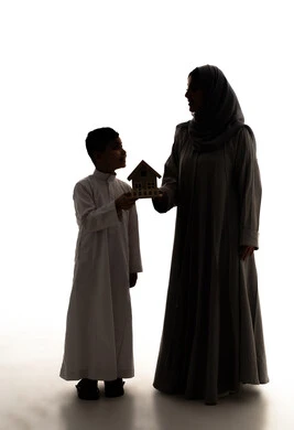Buying and selling real estate, the concept of owning a new home, a silhouette of a Saudi Arabian Gulf mother wearing a hijab and an abaya holding a small wooden model of a house with her son, the concept of family stability and the pursuit of buying a modern house, full-body, white background, silhouette.