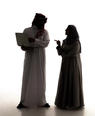 Business management and organization, using modern and advanced technical devices, remote work, a Saudi woman in a hijab pointing to something, browsing social media, a silhouette of a Saudi Gulf Arab man wearing a white thobe and a ghutrah using a laptop, full-body, white background, silhouette.
