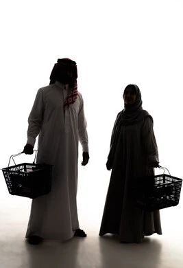 Enjoying shopping in malls and commercial centers, buying necessities and essential items, taking advantage of offers and discounts, a silhouette of an Arab couple from the Gulf, Saudi, wearing traditional attire carrying a shopping basket, purchasing products from the supermarket, full-body, white background, silhouette.