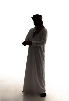Modern electronic entertainment devices and technologies, spending enjoyable and entertaining time, interaction and immersion with video games and PlayStation, a silhouette of an Arab Gulf Saudi man wearing a white thobe and ghutrah holding a game controller in his hand, full body, white background, silhouette.