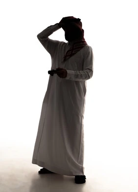 Gestures of loss and disappointment, a silhouette of a Saudi Arabian Gulf man wearing a white thobe and a ghutrah holding a game controller with his hand on his head showing expressions of sadness and discontent, having a good time playing video games, enjoying modern technologies and gadgets, full-body, white background, silhouette.