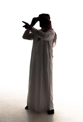 الاشارة الى شيء ما ، رؤية الاشياء البعيدة عبر التلسكوب, حب الاستكشاف و المغامرة,  صورة ظلية لرجل عربي خليجي سعودي يرتدي الثوب الابيض و الشماغ يحمل بيده منظار ثنائي العينين, صورة الجسم بالطول الكامل, خلفية بيضاء ، سولوليت